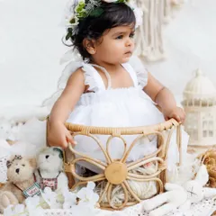 A side profile of the little girl in the wicker basket, showing off the delicate details of her dress and the boho-chic setup.