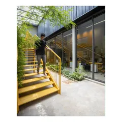 The bright yellow staircase is a central design feature, adding a pop of color and energy to the office. It connects the floors while acting as a sculptural element within the courtyard space.