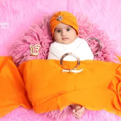 A sweet little sardar looking right at the camera. For this Punjabi themed infant shoot, I used a bright orange turban and a soft pink background.