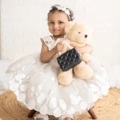 A sweet toddler girl in a beautiful white party dress, hugging her teddy bear. A classic and timeless child portrait.