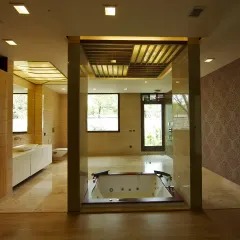 This attached bathroom in the Sachdeva Farmhouse is a spacious, modern retreat with a sunken Jacuzzi tub as its focal point. Warm stone finishes, wooden flooring, and patterned wallpaper create a refined, spa-like ambiance.
