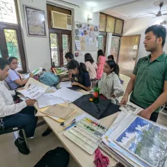 A typical day at the studio, with students deeply engaged in their work. An instructor is reviewing a student's landscape paintings while others continue with their drawing and painting exercises.