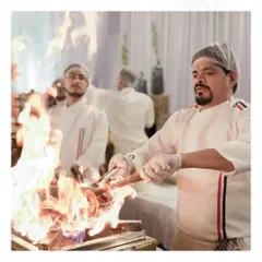 We bring the heat and drama of a live kitchen to your event. Here, one of our chefs is using the flambé technique to prepare a dish, creating an exciting and interactive culinary show for your guests.