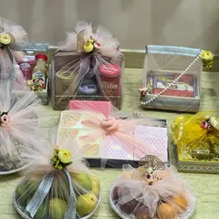 A closer view of the trousseau items, showing how I wrap each piece individually. This includes fruit platters, gift boxes, and other essentials, all decorated with matching net and floral toppers.
