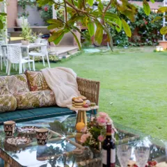 A festive outdoor table setting, ready for a garden party. The view looks across a manicured lawn, suggesting a perfect space for celebrations and cozy gatherings under the open sky.