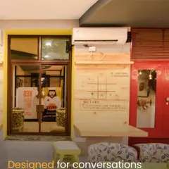 This nook in the cafe is designed for conversations and community. The interactive tic-tac-toe board on the wall and the comfortable, patterned seating create a playful and engaging corner for guests to enjoy.