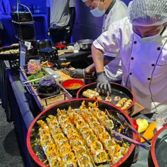 A close-up of the action at our live sushi station. We use high-quality ingredients to prepare a variety of rolls, from classic tempura to inventive modern creations, ensuring a premium experience.