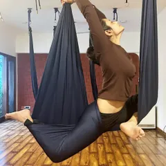 A beautiful aerial pose demonstrating a deep, supported backbend. The silk hammock allows for greater freedom of movement and spinal decompression.