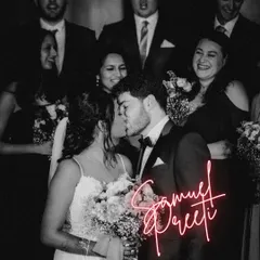 A fun and modern photo of an Indian-Western couple kissing, surrounded by their diverse group of friends and family.