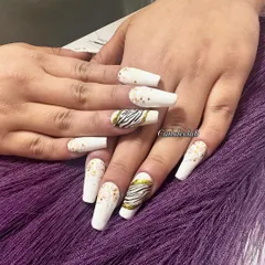 A chic and stylish set featuring matte white nails with gold accents and a bold zebra print accent nail.