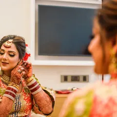 "Sajna tere liye sajna." The bride puts on her earrings, a final touch before she is ready. This over-the-shoulder shot creates an intimate and personal perspective.