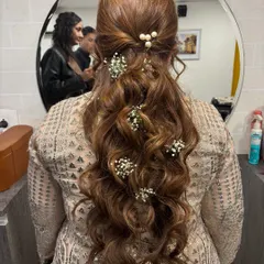 A beautiful half-up, half-down hairstyle for a festive occasion. The long, flowing curls are accented with delicate baby's breath and pearls for a look that is both graceful and traditional.