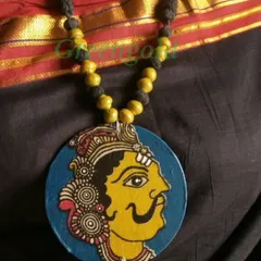 Another example of a Kalamkari fabric pendant, this time featuring the face of a royal figure with a magnificent mustache. The yellow and blue colors are characteristic of this art form.