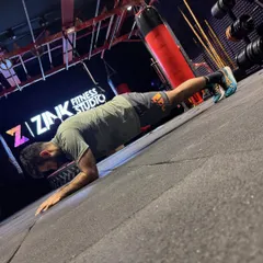 A strong core is the foundation of all movement. This client demonstrates a solid plank in front of our Zink Fitness Studio logo, showcasing the kind of foundational strength we build here.