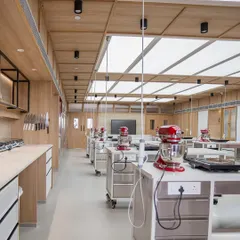 A side view of our baking classroom shows how every student gets their own space. Each station is equipped with a personal induction cooktop and a KitchenAid mixer, so everyone can participate fully in every step of the baking process.