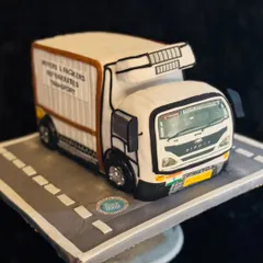 A full view of the sculpted truck cake, set on an edible road. This shows the scale and precision involved in creating such a detailed 3D cake.