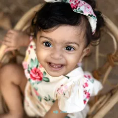 A close-up portrait capturing the brightest smile and sparkling eyes during an outdoor first birthday shoot.
