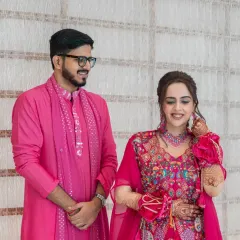 A sweet moment between the bride and groom during their haldi function, dressed in vibrant pink.