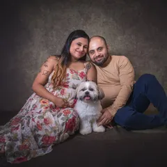 A relaxed and happy portrait of an expecting couple sitting on the floor with their dog nestled between them. This image radiates warmth and the love they share for their pet and each other.