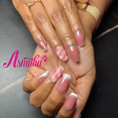 This set of nail extensions combines several popular techniques. It features a soft pink base with marble art on the ring finger and a delicate French tip with a glitter line.