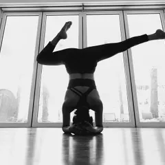 Finding new perspectives is a beautiful part of yoga. This artistic shot captures a moment of play and focus in a Salamba Sirsasana (Supported Headstand) variation, silhouetted against the light of the studio windows.