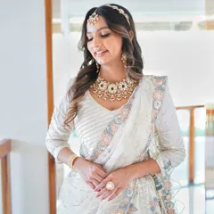 A full-length shot of the bride in her beautiful white lehenga, the jewellery adding a touch of regal elegance.