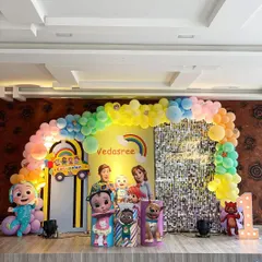 For the little ones, I design colorful themes like this Cocomelon party. It features a rainbow balloon arch, a silver shimmer wall, life-sized character cutouts of JJ and his friends, and a light-up marquee number '1' for a first birthday.