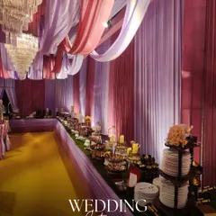 We transform wedding catering into a grand visual experience. Here, a lavish buffet spread is set under elegant pink and lavender drapes, creating a breathtaking dining ambiance for a large wedding celebration.