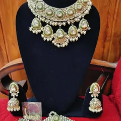 A full bridal set featuring a Polki kundan necklace, matching jhumkas, a mathapatti, and hathphool.