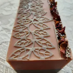 A full, fresh loaf of my Charcoal Rose soap, just poured and decorated. The top is adorned with dried rose petals and a delicate stencil pattern, hinting at the beauty within.