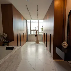 A luxurious walk-in closet with floor-to-ceiling veneer wardrobes, marble flooring, and a central jacuzzi tub.