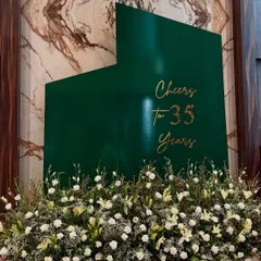 Celebrating 35 years deserved a statement piece. We designed this minimalist yet bold backdrop, combining a rich emerald green with elegant gold lettering and a bed of fresh white flowers to create a look that was both modern and timeless.
