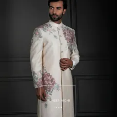 An ivory silk Achkan where artistry blooms. The clean, straight cut is a canvas for blush-pink and sage-green floral embroidery that sweeps across the shoulders and cuffs, a testament to modern elegance and timeless craftsmanship.