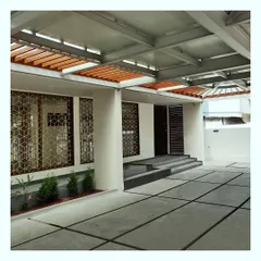 A view of the entrance and parking area of a modern residence, featuring geometric grills and a cantilevered canopy.