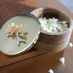 This version of our keepsake box features a wooden base and a polished gold lid with a dual-tone floral accent. The mix of materials adds a warm, organic touch to this elegant storage piece.