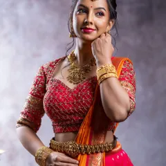 This stunning half saree combines a bright pink skirt with an orange tissue dupatta. The look is completed with a hand-embroidered blouse, making it a perfect rental for weddings or pre-wedding events.