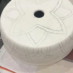 The journey of a lampshade begins with a pencil sketch on greenware (unfired clay). This is where the design is carefully planned before any carving or color is added.