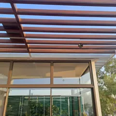 A detailed view of the wooden pergola structure built over a glass roof. This design element adds architectural character while providing partial shade, creating a comfortable and visually interesting environment.