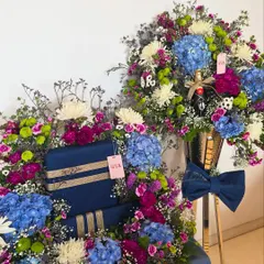 A sophisticated and grand display in shades of royal blue and purple. This setup includes a large floral arrangement for gifts and a matching bouquet with a bottle of champagne.
