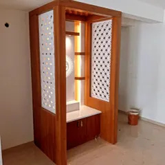 A custom-built wooden pooja unit with a beautiful polish. The finish complements the intricate jali work and integrated lighting.