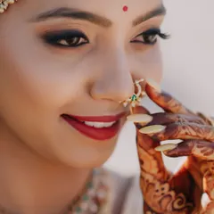 A close-up of this bride's classic look, featuring a bold red lip and defined, kohl-rimmed eyes. Her expression captures the serene beauty and anticipation of her wedding day.