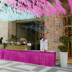 A cohesive design ensures a seamless experience. Here, the vibrant entrance decor flows into the outdoor party area, complementing the colorful buffet setup and creating a unified, festive atmosphere for the corporate event.