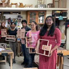 A group of interior design students proudly displaying the complex shelf designs they built in a single day.