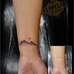 This minimalist mountain range tattoo was designed specifically to cover a wrist scar. By placing the design directly over the scar, we turned an old mark into a beautiful and meaningful piece of art.