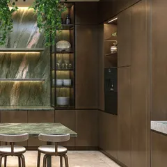 A closer look at the kitchen's material palette, showing the contrast between the polished green stone, the brushed metal finish on the cabinetry, and the warm tones of the breakfast stools.