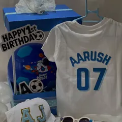 Here are all the goodies from the football-themed first birthday hamper for Aarush. It includes a personalized t-shirt, a custom cap, cool sunglasses, and a mini football, all packed in a themed box.