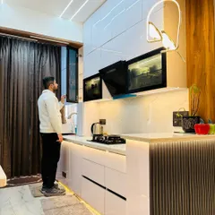 This is a close-up of a high-end modular kitchen I designed, featuring handleless white gloss cabinets and a built-in chimney. The under-cabinet LED strip lighting not only illuminates the countertop but also adds a touch of modern elegance.