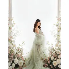 A full-length portrait showcasing a dreamy, ethereal look. The soft green gown and floral frame create a picture of a mother-to-be in her own secret garden.