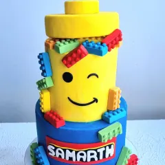 A close-up of the Lego cake, showing the personalized name and the playful arrangement of the fondant bricks.