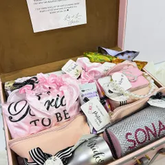 A peek inside a fully loaded bridal trunk. This hamper is packed with personalized items like a "Bride to be" sash, a custom tumbler, pouches, and a heartfelt note.